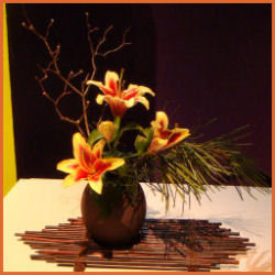 three lily blooms with a vertical bare branch and horizontal piece of pine