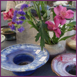 shallow blue and red pottery dishes with flower frogs and a few fresh blooms