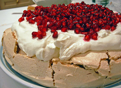 A homemade pavlova decorated with pomegranate seeds and chantilly cream