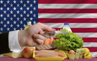 man stretching out credit card to buy food in front of complete wavy national flag of usa