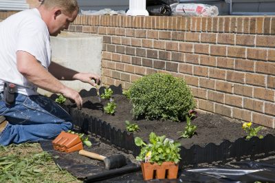 Man planting flowers in garden, dressing up landscape to help sell home